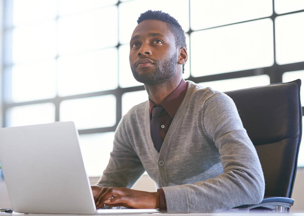 Buscando en línea para otra oportunidad de negocio lucrativa. un joven hombre de negocios reflexivo usando un ordenador portátil en una oficina - Foto, imagen