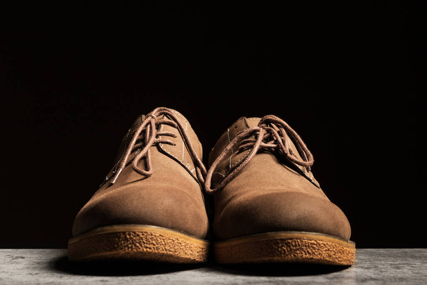 Мужчины замшевые коричневые низкие ботинки со шнурками на черном фоне. - Фото, изображение