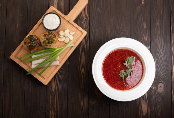 Borscht. Traditional Ukrainian dish in a plate on a wooden background, top view. Copy space - Foto, Imagen