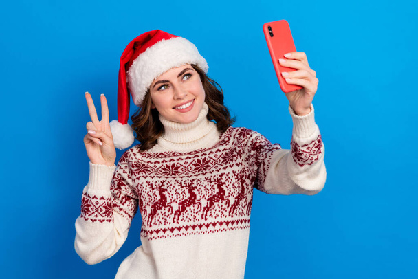Photo of charming lady wear ugly sweater use social media app make self picture video record v-sign isolated on blue color background. - Φωτογραφία, εικόνα