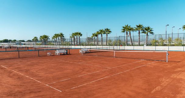 Baseline and net of an empty clay tennis court on a sunny day - Zdjęcie, obraz