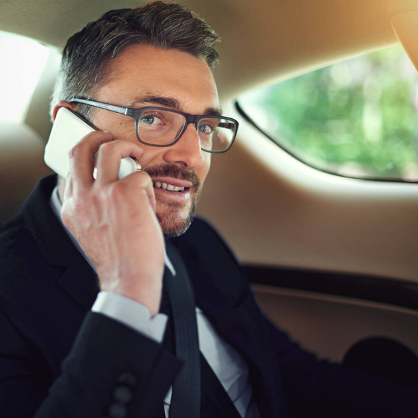 Im turning into your street right now. a businessman using his cellphone while sitting in the backseat of a car - Foto, Bild