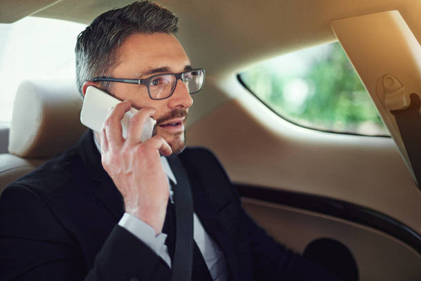Im headed into the office right now. a businessman using his cellphone while sitting in the backseat of a car - Foto, Imagem