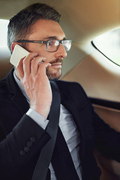 Alle meine Treffen heute absagen. ein Geschäftsmann benutzt sein Handy, während er auf dem Rücksitz eines Autos sitzt - Foto, Bild