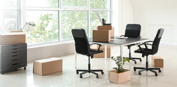 Caixas de papelão com pertences e móveis em novo escritório no dia em movimento
 - Foto, Imagem