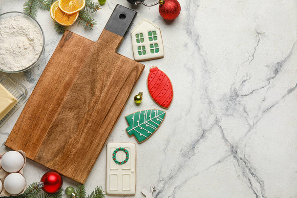 Composition with wooden cutting board, Christmas cookies, ingredients and decorations on light background - Fotoğraf, Görsel