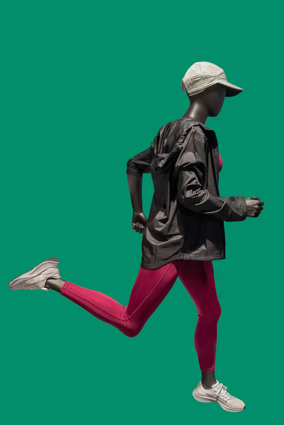 Immagine di un manichino donna che corre indossando abbigliamento sportivo isolato su verde - Foto, immagini