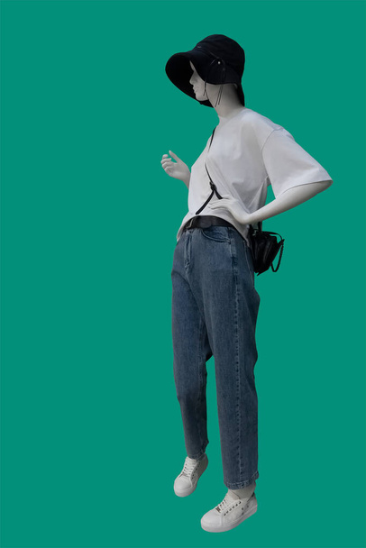 Полная длина изображения женского манекена дисплея в белой блузке с короткими рукавами и синими джинсами, изолированными на зеленом фоне - Фото, изображение