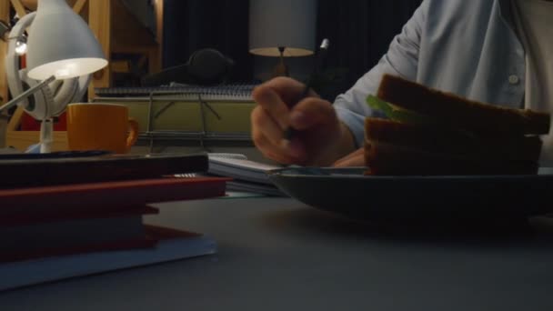 Guy arms writing pencil at table closeup. Unknown person preparing schedule in notebook zoom on. Unrecognizable man making notes holding pen at remote evening workplace alone. Freelance concept  - Footage, Video