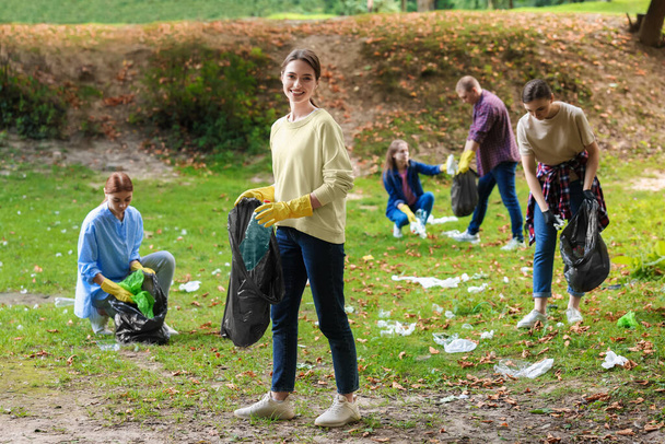 Group of people with plastic bags collecting garbage in park - Fotografie, Obrázek
