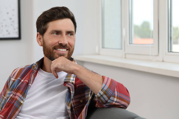 Smiling bearded man looking away at home - Foto, Imagen
