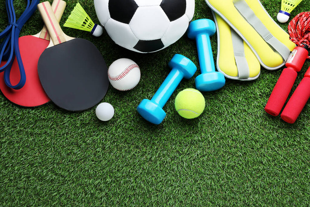 Set of different colorful sports equipment on green grass, flat lay. Space for text - Фото, изображение
