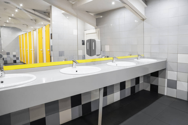 Public toilet interior with sinks, mirror and colorful tiles - Fotoğraf, Görsel