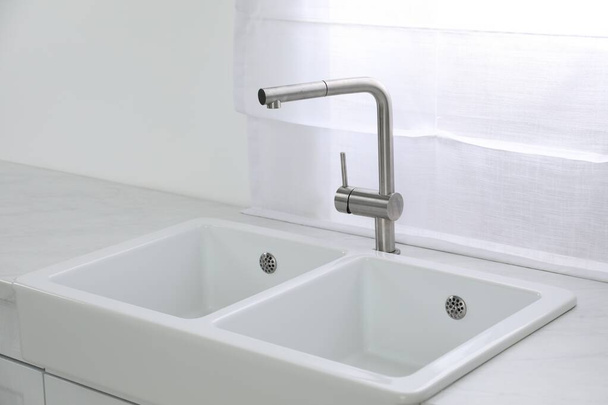 Modern sink and water tap near window in kitchen. Interior design - Fotó, kép