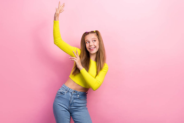 Portrait of adorable playful girl straight hair dressed yellow long sleeve look empty space dancing isolated on yellow color background. - Foto, immagini