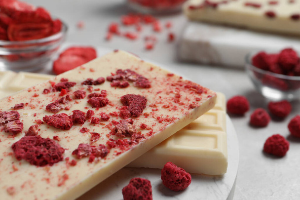Chocolate bars with freeze dried raspberries on light marble table, closeup - 写真・画像