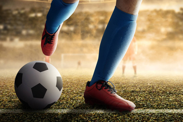 Football player man in a blue jersey kicking the ball on the football field - Foto, imagen