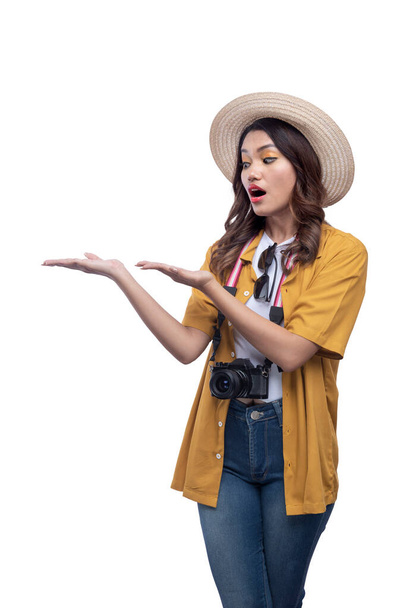 Asian woman with a hat and camera with open palm pointing at something isolated over white background - Foto, imagen
