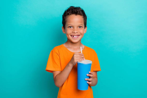 Photo of cute adorable little guy dressed orange t-shirt enjoying tasty drink isolated teal color background. - Photo, Image