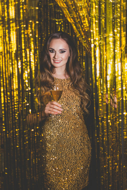 Piękna kobieta celebryci z makijażu noszenie złotej sukienki na złotym bokeh tle - Zdjęcie, obraz