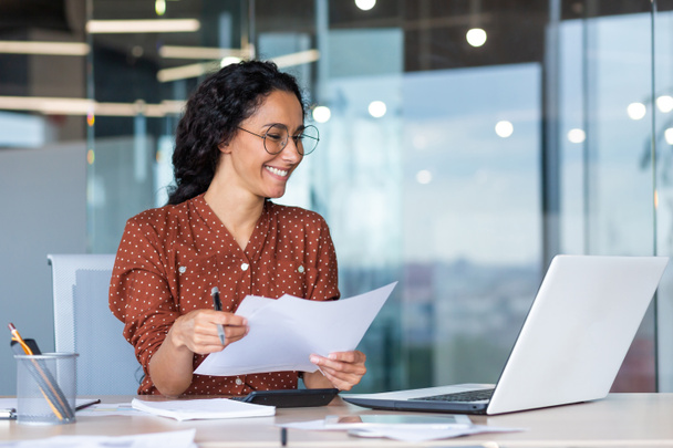 Mulher de negócios satisfeita e feliz bem sucedida trabalhando dentro do escritório moderno, mulher hispânica em óculos e camisa usando laptop no trabalho, - Foto, Imagem