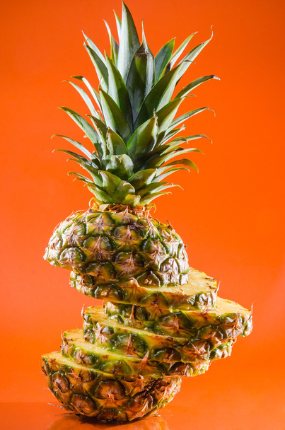 Artistic sliced, standing pineapple on orange background, vertical shot - Photo, Image