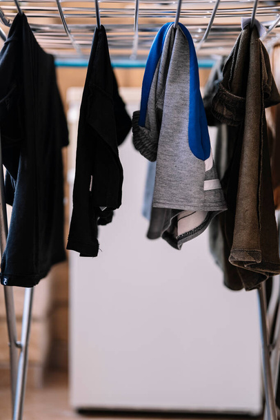 Kleider hängen an einer Wäscheleine im Haus. - Foto, Bild