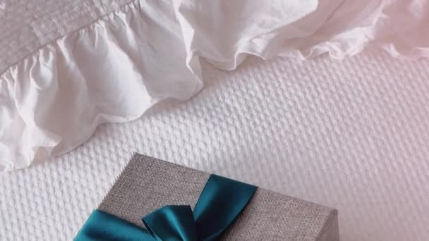 Holiday present and luxury online shopping delivery, wrapped linen gift box with blue ribbon on bed in bedroom, chic countryside style, close-up - Video
