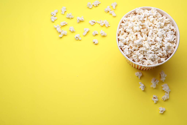 Paper bucket with delicious popcorn on yellow background, flat lay. Space for text - Fotografie, Obrázek