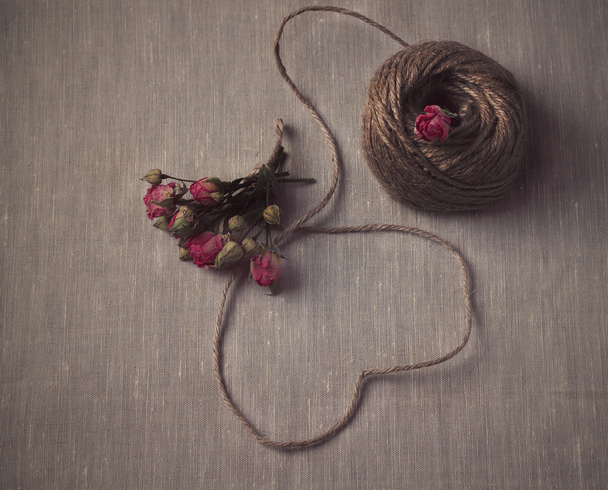 herzförmige Naturschnur mit einem Strauß getrockneter Rosen - Foto, Bild