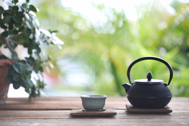 Metal tea pot and tea cup and plant pot on wooden table - Foto, Imagen
