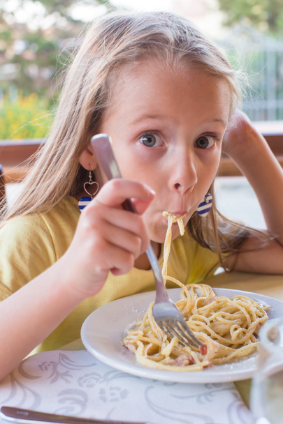 aranyos kislány spagetti eszik a szabadban étterem - Fotó, kép