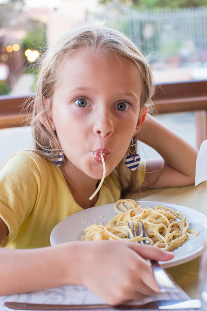 schattig meisje eten spaghetti in openlucht restaurant - Foto, afbeelding
