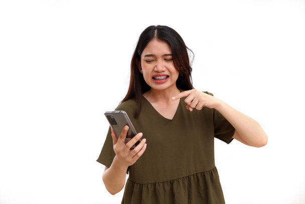 Angry young asian woman with her cell phone. Isolated on white background with copyspace - Foto, Imagem