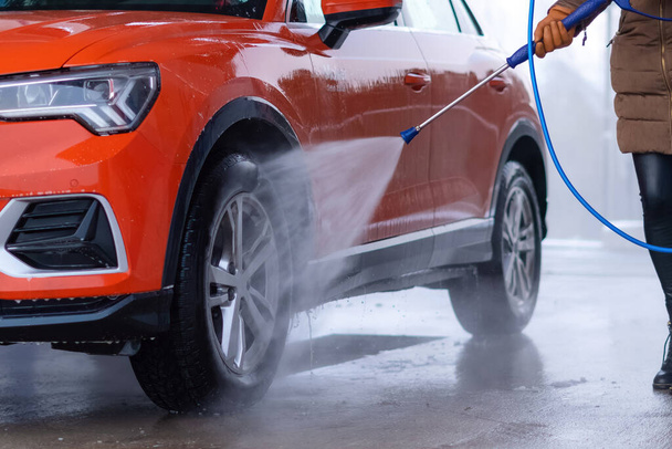 Közelkép a nő mosás az autó nagy nyomású vízzel önkiszolgáló autómosó. - Fotó, kép
