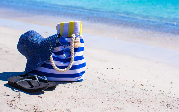 Sombrero de paja, bolsa y toalla en la playa tropical blanca
 - Foto, Imagen