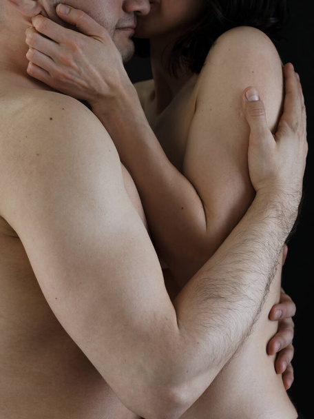 Güzel, tutkulu, aşık, çıplak bir çift. Bir erkek ve bir kadın birbirlerinin kollarında. Karanlık bir arkaplanda fotoğraf. - Fotoğraf, Görsel