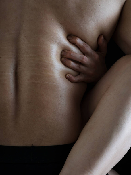 Ein Mann und eine Frau liegen sich in den Armen. Die Beine und Arme von Frauen umarmen einen kräftigen muskulösen männlichen Rücken. Nackte Körper. Foto ohne Gesicht. - Foto, Bild