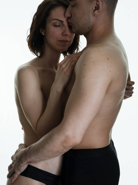 愛の美しい情熱的な裸のカップル。お互いの腕の中の男と女。白い背景の写真. - 写真・画像