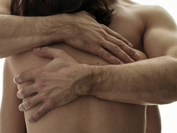 A woman in the arms of a man. Beautiful male hands on a woman's back. Close-up on a white background. Photo without a face. - Фото, зображення