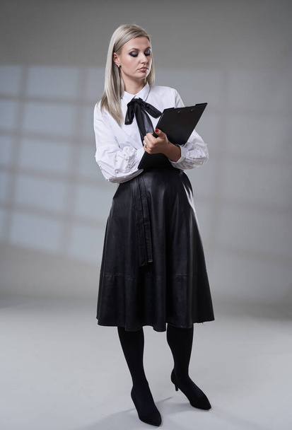 Business woman in black skirt and white shirt, full length studio portrait on gray background - Photo, image