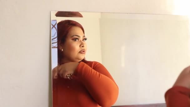 Hiszpanka plus kobieta wielkości czesająca włosy przed lustrem. meksykański pulchny - Materiał filmowy, wideo