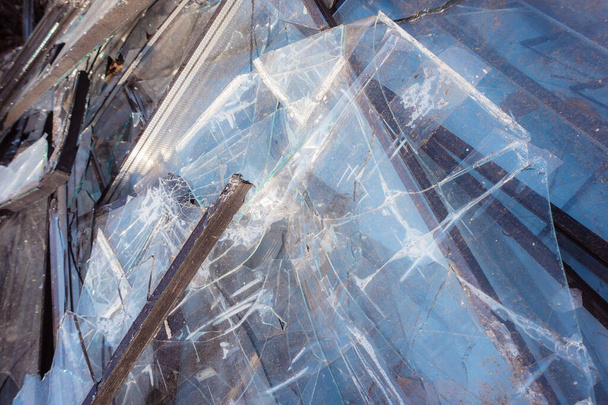Jede Menge Glasscherben. Zerbrochene Fenster eines Hochhauses sammelten sich auf einem Mülleimer. Folgen eines massiven Raketenangriffs. Folgen militärischer Aktionen. - Foto, Bild
