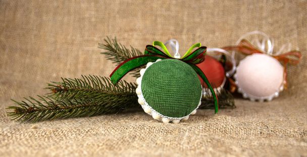 Weihnachtsspielzeug mit Schleifen und einem Weihnachtsbaumzweig auf einem Hintergrund aus Klecksen. Weihnachten Hintergrunddekoration. Festlicher Neujahrshintergrund aus Plüschtieren - Foto, Bild