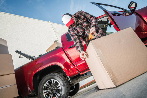 Professional Mover tiivistys pahvilaatikko käyttäen pakkausteippiä turvata sen turvallisen kuljetuksen. Siirtopalvelujen teema. - Valokuva, kuva