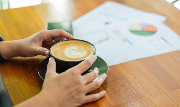Nahaufnahme Hand trinkt heißen Kaffee mit Arbeit, entspannen Sie sich - Foto, Bild