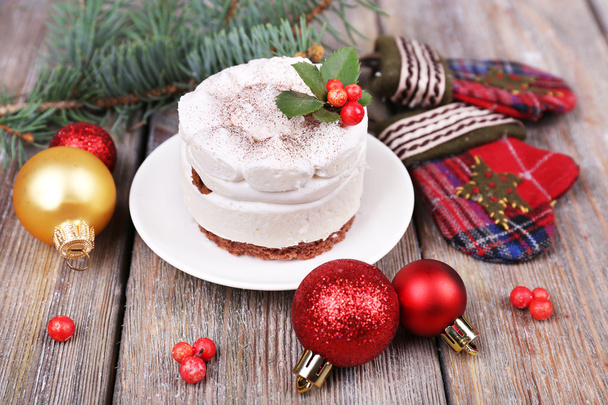Delicious cake on saucer with holly and berry on Christmas decoration and wooden background - Fotó, kép