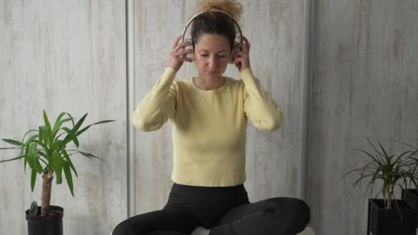 1人の女性大人白人女性千年紀ヘッドフォンとデジタルタブレットを使用してオンラインガイド付き瞑想のための精神ヨガを練習自宅で床の上で目を閉じて現実の人々コピースペース - 映像、動画