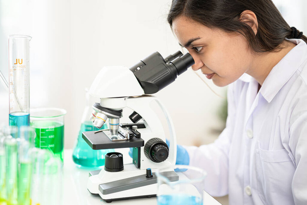 επιστήμονας που κοιτάζει μέσα από ένα μικροσκόπιο σε ένα εργαστήριο. Νεαρός επιστήμονας κάνει κάποια έρευνα. επιστήμονας που κοιτάζει μέσα από ένα μικροσκόπιο σε ένα εργαστήριο. Νεαρός επιστήμονας κάνει κάποια έρευνα. - Φωτογραφία, εικόνα