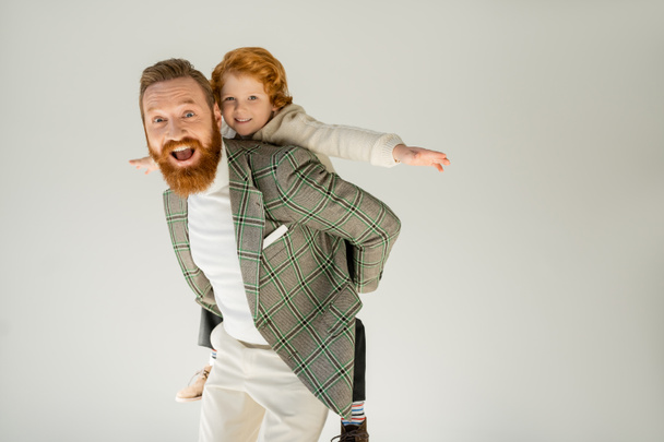 Excited bearded father playing with son isolated on grey  - 写真・画像